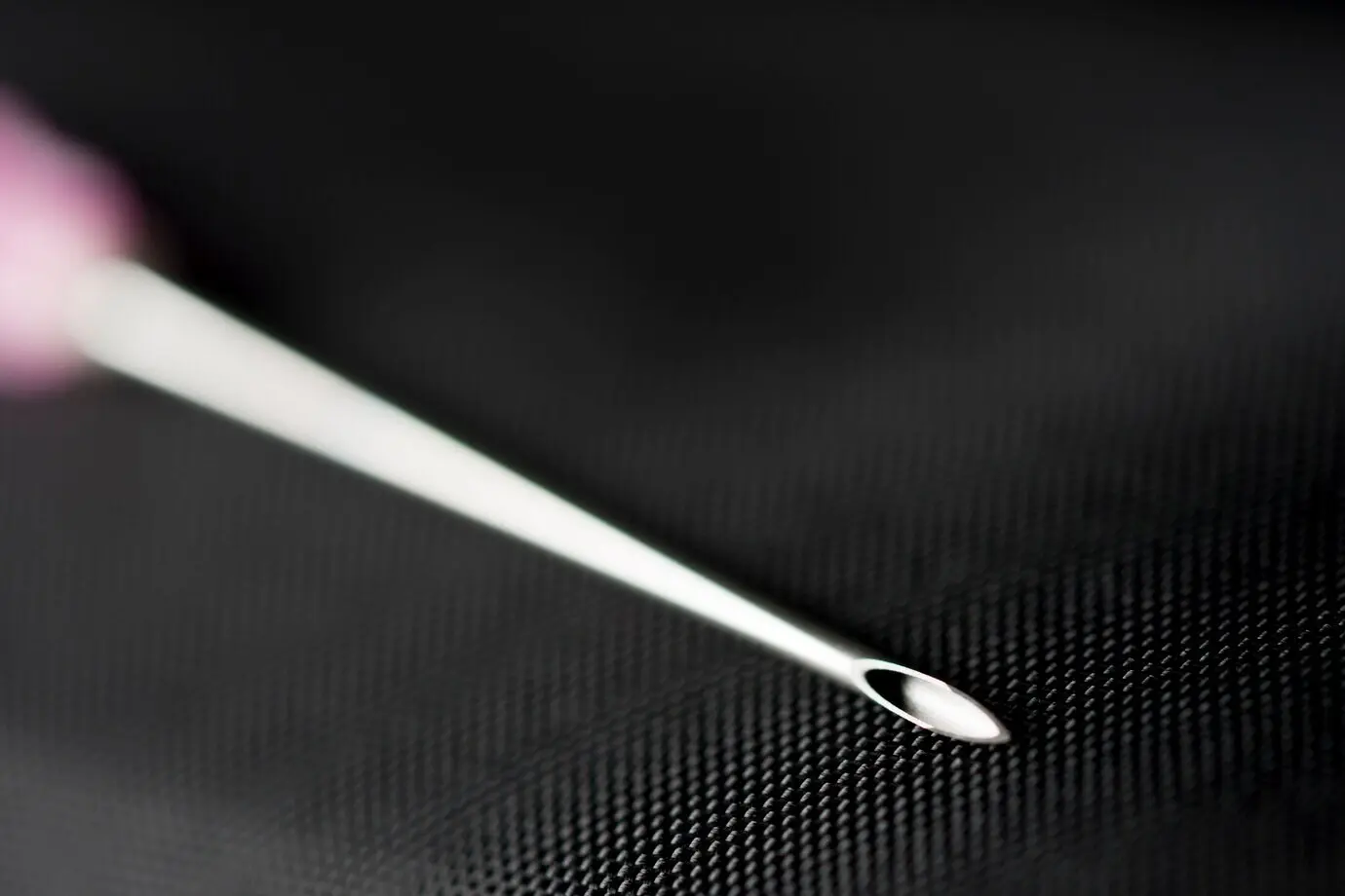 Игла шприца на чёрном фоне